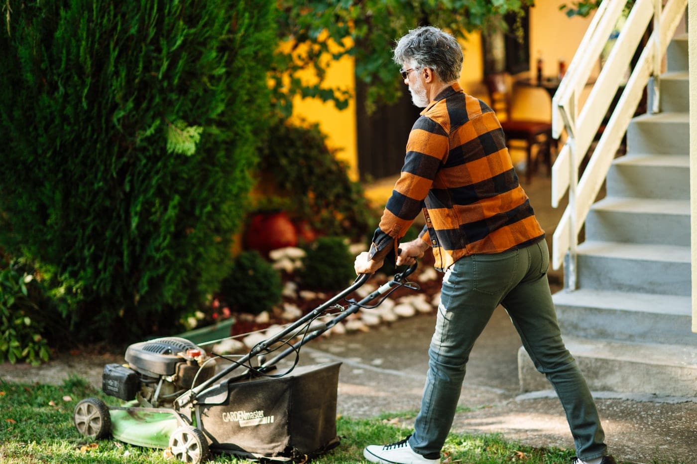 Person mowing a residential lawn with a push mower in Guelph