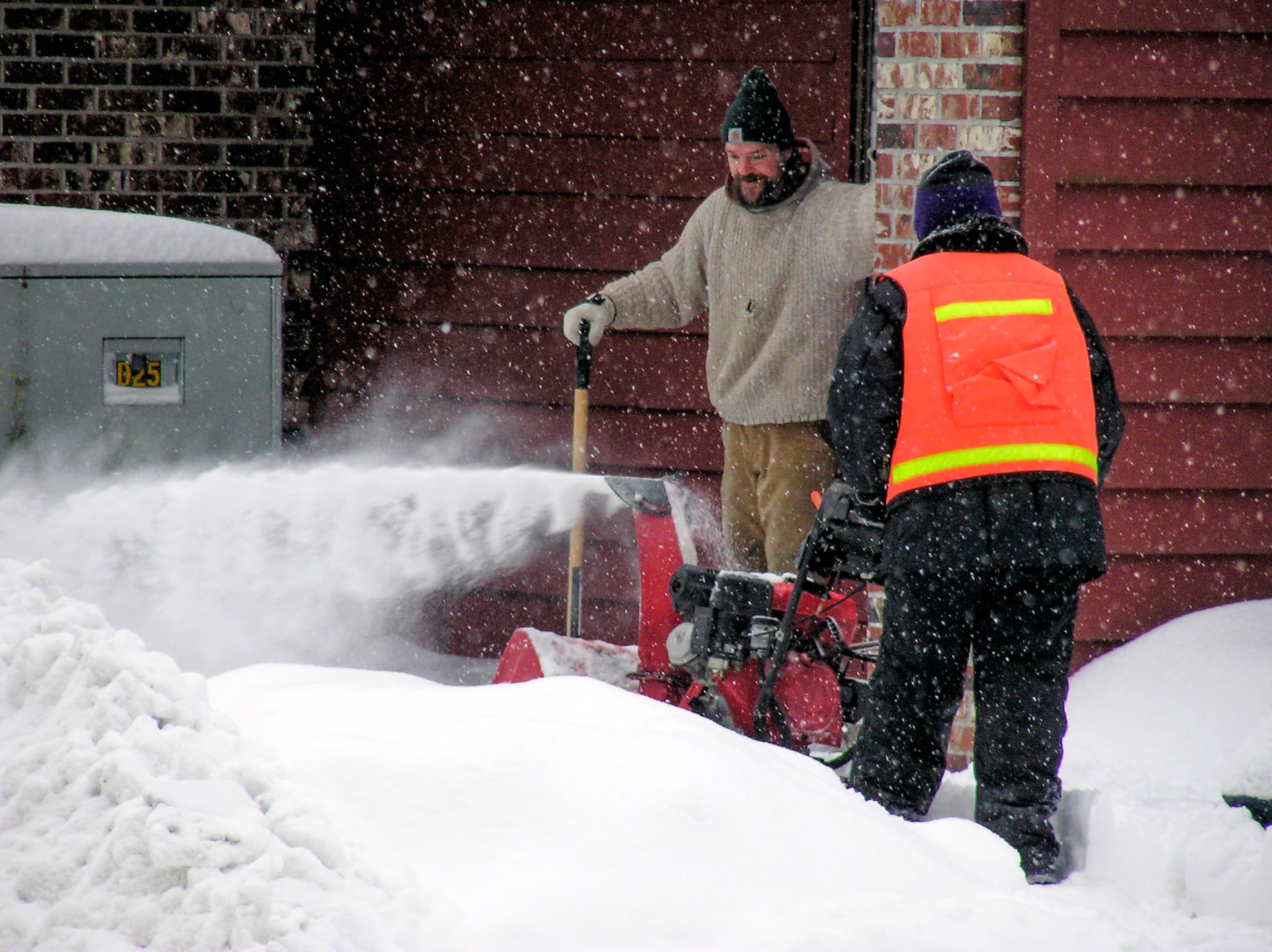 Snow removal professional clearing a residential driveway with a snow blower